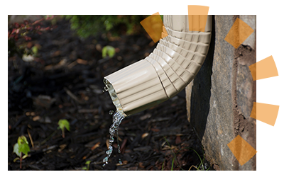 A downspout letting out rainwater at the ground level.